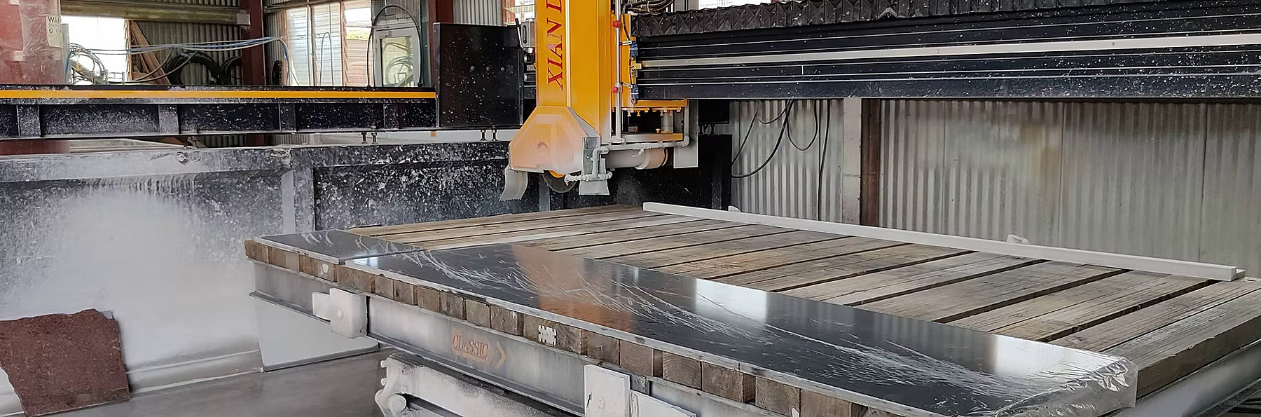 Bridge saw cutting a polished black stone slab