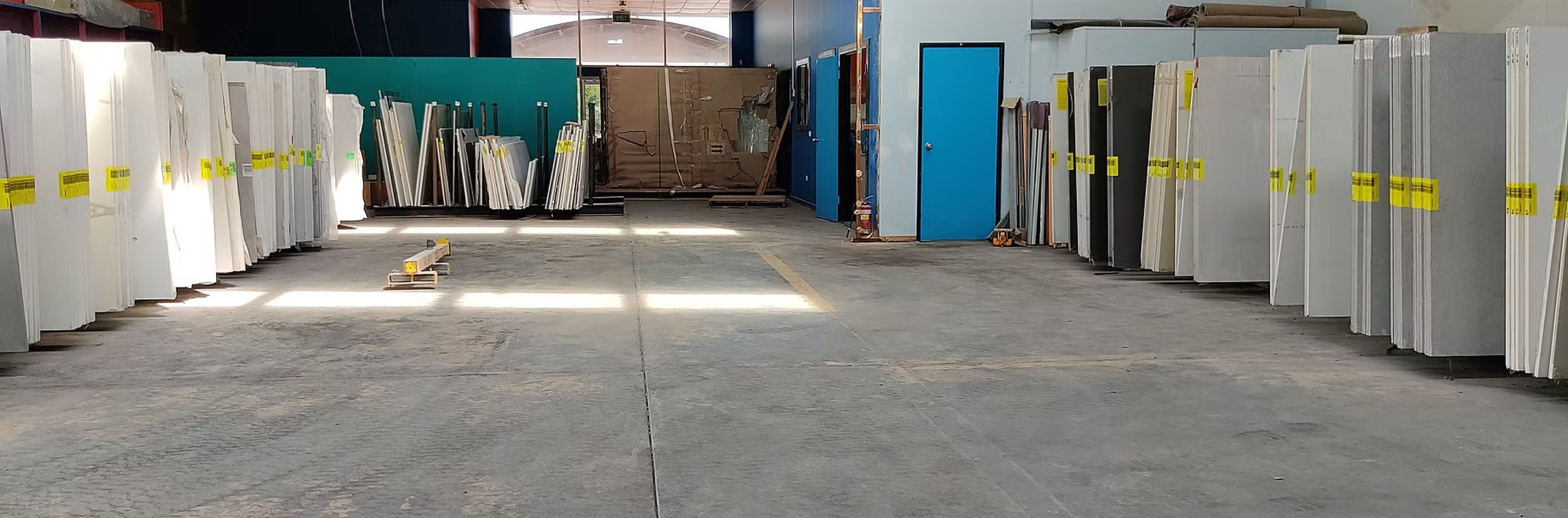 Racks of full stone slabs with yellow tags inside the One Stone Works slab yard